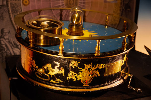 orrery circular object with brass handle to turn solar system and pictures of phoenixes painted on the side
