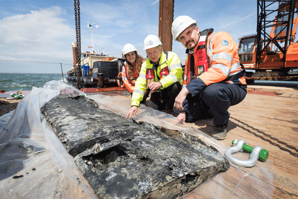 three people with plane wing lifted from seabed