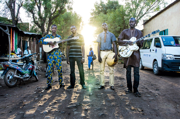 four men stand in the street with their musical instruments