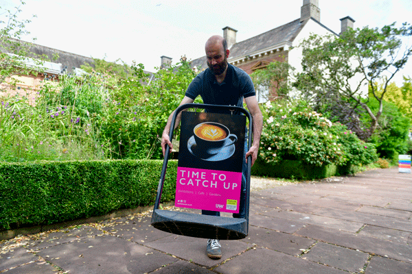 man carries sign with coffee cup on it