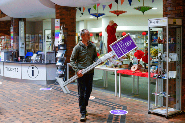 man holds sanitiser sign