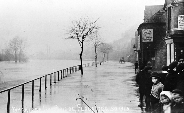 children stand at the edge of flood in black and white photo of ironbridge gorge