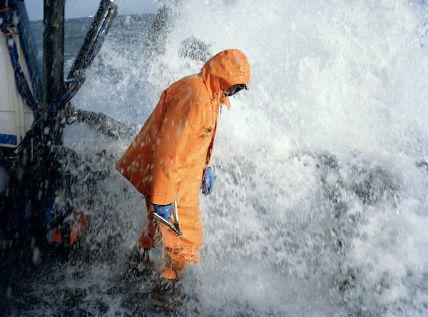 person in orange waterproof drenched by sea