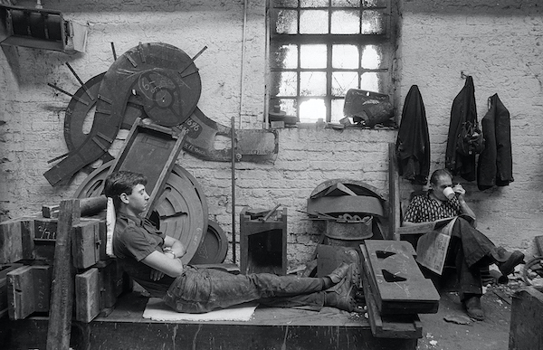 black and white photo young man rests in machine shop