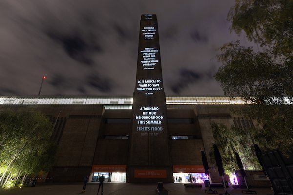 words about the climate crisis projected onto the chimney of Tate Modern