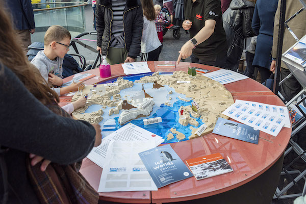 child and aduits sit at a table of activities based around a circular picture of the world