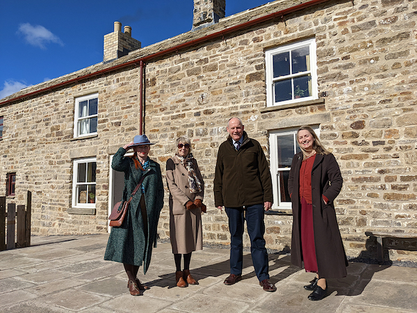 people stand outside farm building