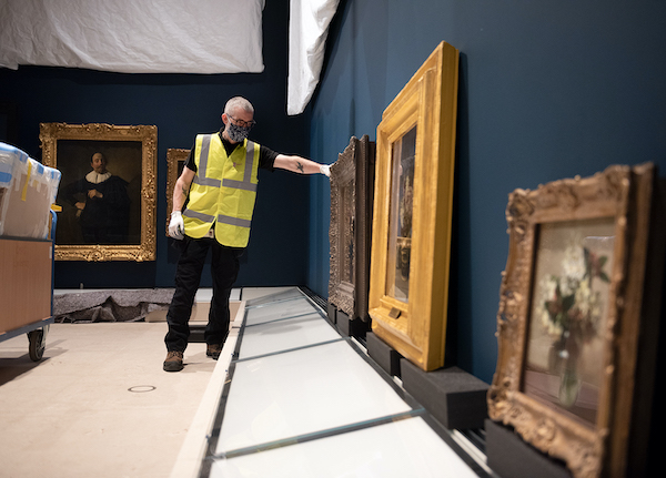 man in high vis jacket among paintings awaiting hang