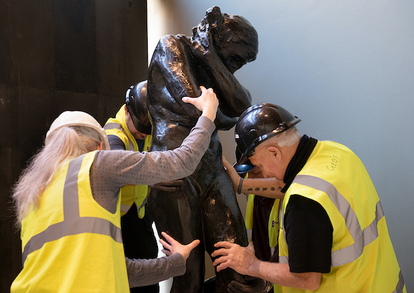 two gallery workers move statue