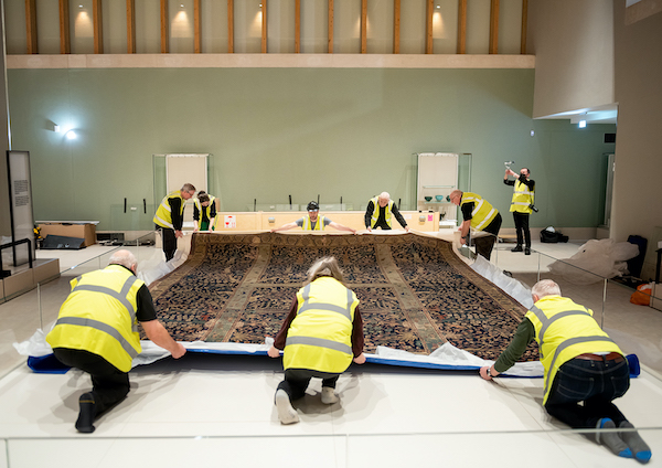 many people in high vis jackets roll out giant carpet