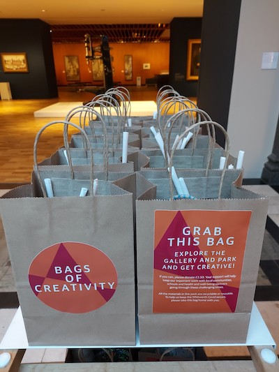 paper bags with bags of creativity written on them against the backdrop of the whitworth gallery