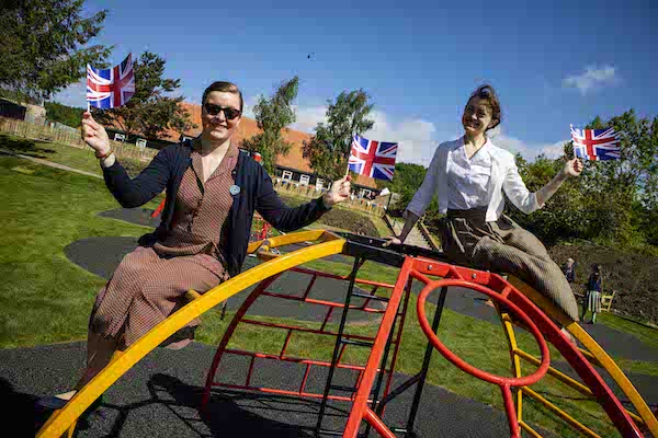 two women waving flags on a climbing frame