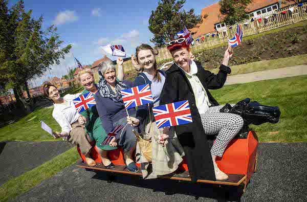 several people sitting on an outdoor park rocking horse