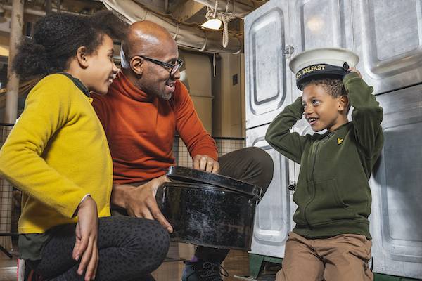 boy in hat with parents at Hms belfast