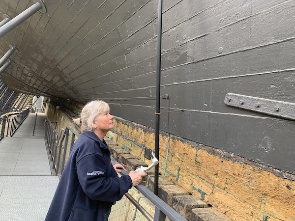 woman looks at hull of hms victory which extends over her head