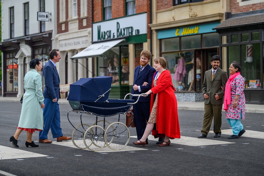 A street scene with people walking across a zebra crossing in the background is the historic high street.