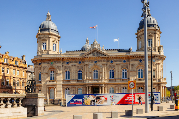 Photograph of the exterior of a large building, the ornate Victorian triangular brick and stone building houses the Hull Maritime Museum, featuring carved stone pillars, arched windows, and three small domes against an open sky