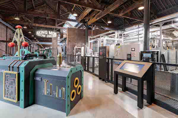 Photograph of museum interactives in the Power Hall a touch screen display to the left and to the right a large black and green interactive with things to touch and pull.