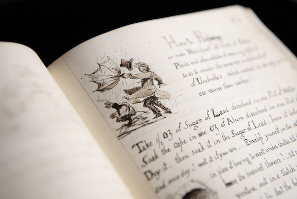 Photograph of a book open at a particular page. On the top of the page is a small illustration of a man trying to keep his umbrella up in the wind and rain. His umbrella has turned inside out. There is also writing on the page 