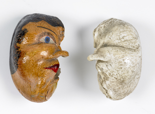 Whale ear bones that resemble human ears, one is painted to look like a human face. 